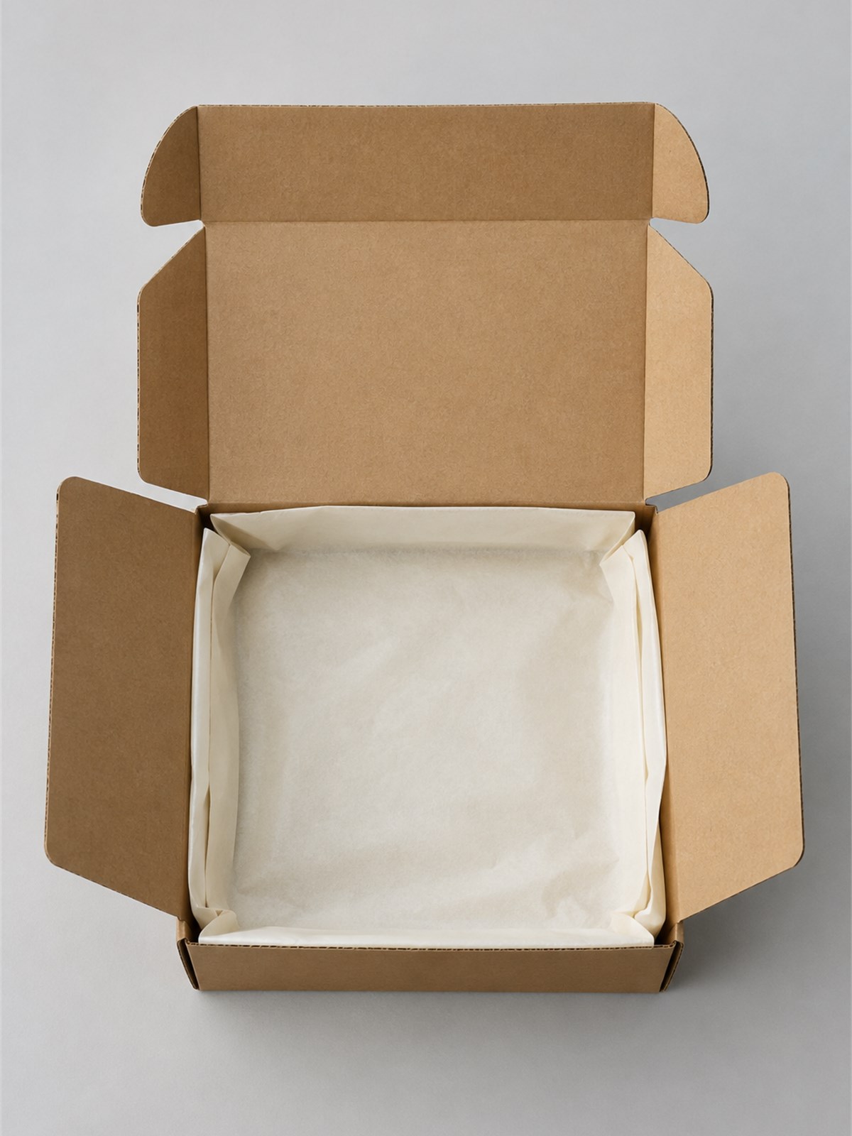Open kraft mailer box with printed interior and paper wrapping, shown on a neutral studio surface